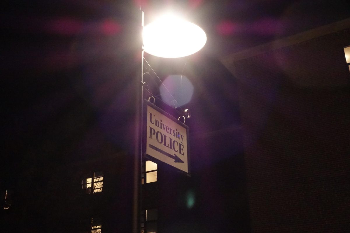 A sign pointing to the Clark University Police Department's location in the basement of Bullock Hall at night time at Clark University, Worcester, MA, Wednesday, Aug. 28, 2024.